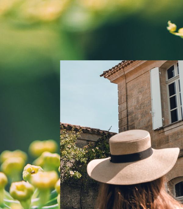 Vue de dos d'une femme portant un chapeau devant la façade du Château